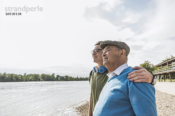 Großvater und Enkel am Flussufer schauen gemeinsam in die Ferne