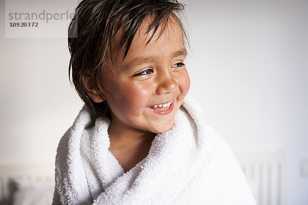 Porträt eines lächelnden kleinen Jungen mit Duschtuch nach dem Baden