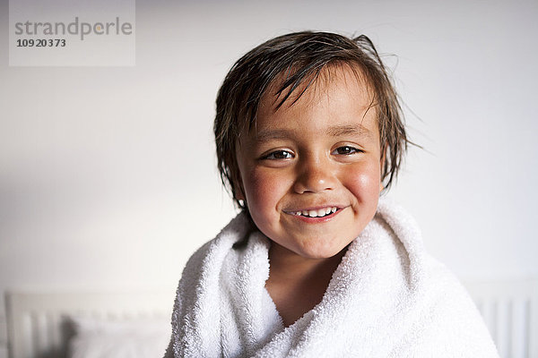 Porträt eines lächelnden kleinen Jungen mit Duschtuch nach dem Baden