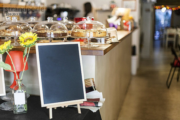 Kuchentheke und Begrüßungstafel im kleinen Cafe