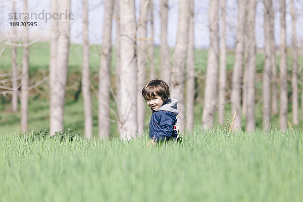 Porträt eines kleinen Jungen  der auf einem Feld spazieren geht.