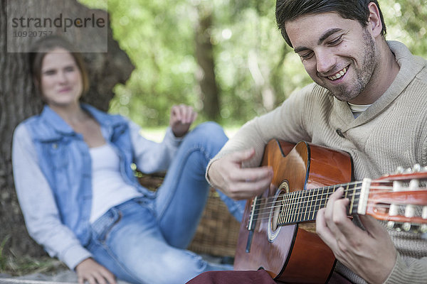 Junges Paar beim Picknick mit Gitarrenspieler