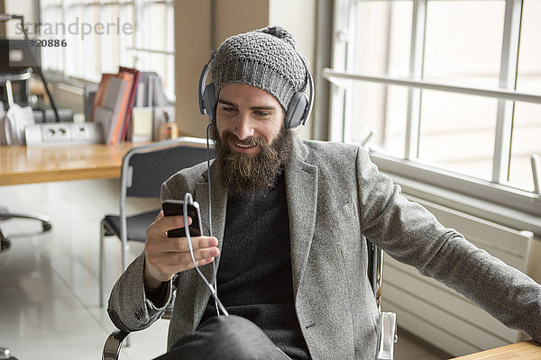 Porträt eines jungen Geschäftsmannes mit Bohnenhut per Smartphone