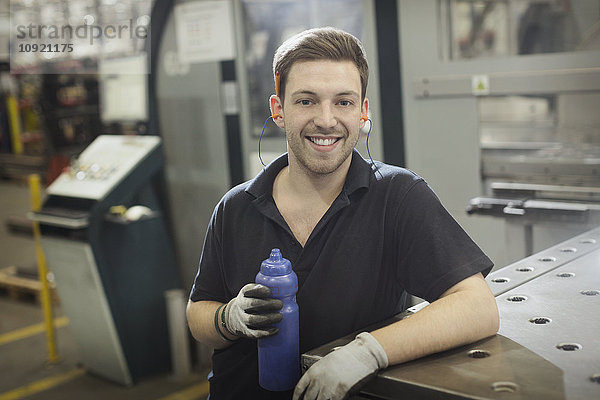 Portrait lächelnder Arbeiter mit Wasserflasche im Stahlwerk
