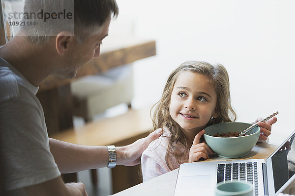 Vater und Tochter beim Frühstücken am Laptop