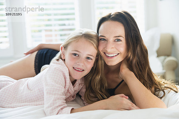 Portrait lächelnde Mutter und Tochter auf dem Bett liegend
