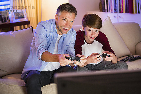 Vater und Sohn spielen Videospiel im Wohnzimmer