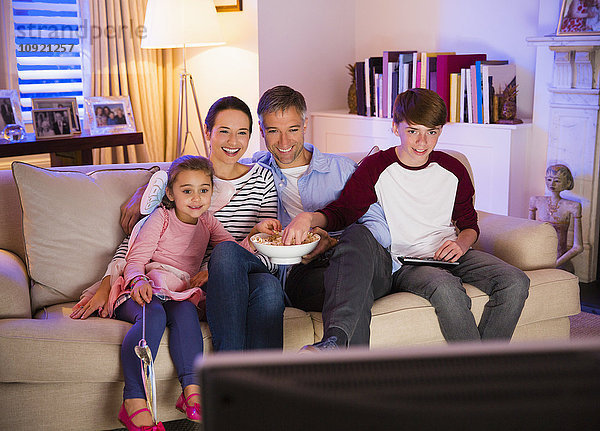 Familie beim Popcornessen und Fernsehen im Wohnzimmer