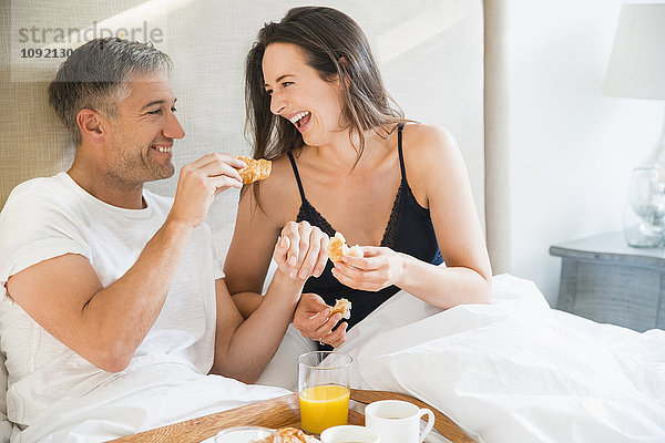 Lachendes Paar beim Frühstück im Bett