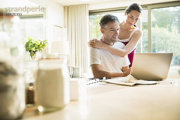 Paar mit Laptop in der Morgenküche