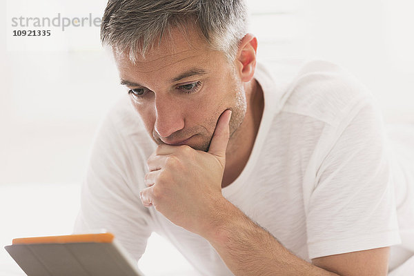 Seriöser Mann mit digitalem Tablett mit Hand am Kinn