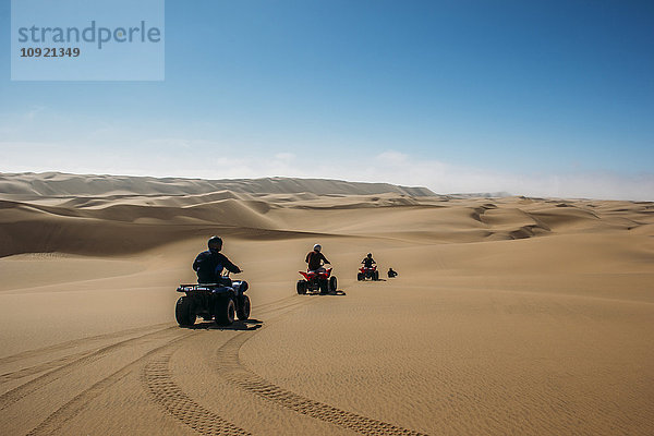 Freunde beim Quadfahren in der sonnigen Wüste  Swakopmund  Namibia