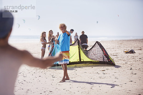 Freunde beim Kitesurfen am sonnigen Strand