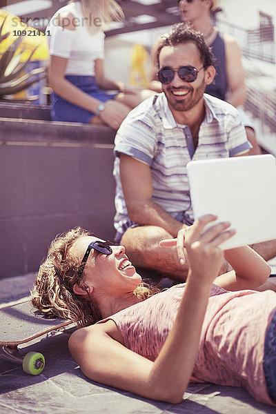 Freunde  die mit dem digitalen Tablett auf dem Skateboard rumhängen