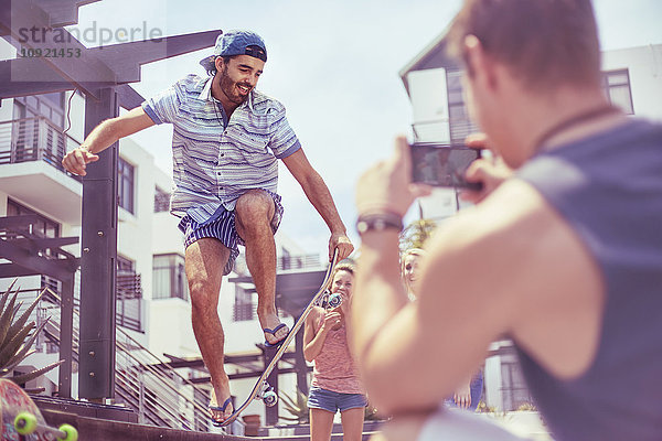 Junger Mann fotografiert Freund beim Skateboard-Stunt