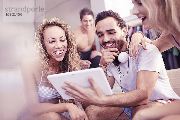 Junge Freunde lachen mit digitalem Tablett