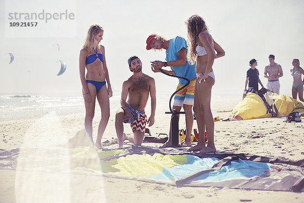 Freunde beim Kitesurfen am sonnigen Strand