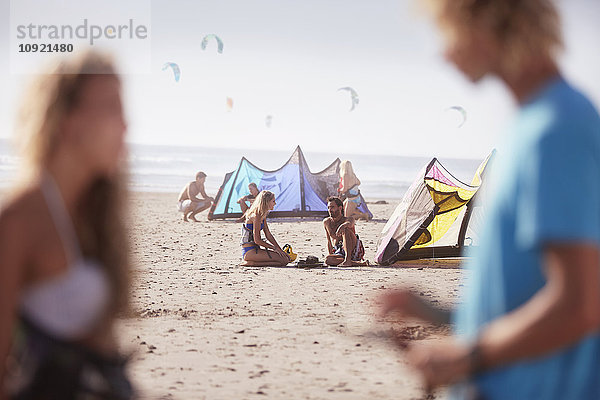 Leute mit Kiteboardausrüstung am sonnigen Strand