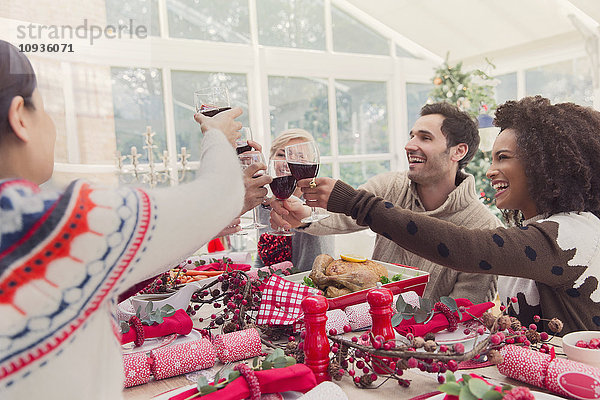 Freunde toasten Weingläser am Weihnachtstisch