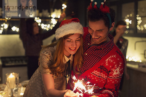 Verspieltes Paar mit weihnachtlichen Wunderkerzen