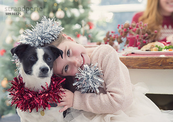 Portrait lächelndes Mädchen umarmender Hund mit Weihnachtsdekoration