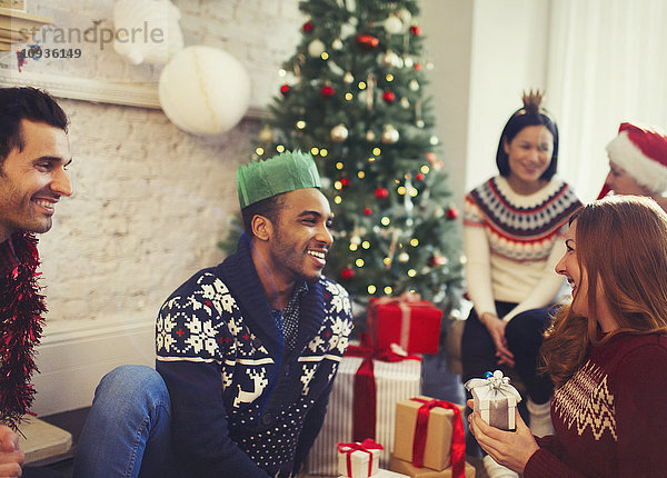 Freunde eröffnen Weihnachtsgeschenke im Wohnzimmer