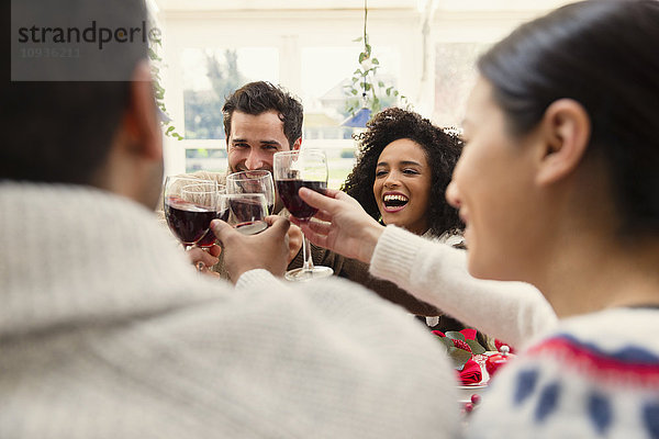 Enthusiastische Freunde stoßen beim Weihnachtsessen auf Weingläser an.