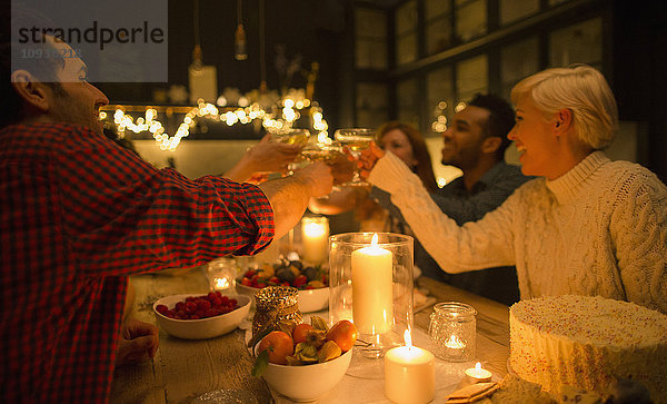 Freunde toasten Champagnergläser bei Kerzenschein Weihnachtsfeier