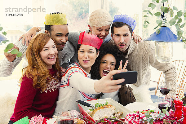 Freunde  die Papierkronen tragen und Selfie zum Weihnachtsessen nehmen