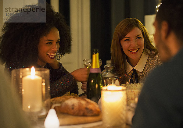 Lächelnde Freunde trinken Champagner am Candlelight-Dinner-Tisch