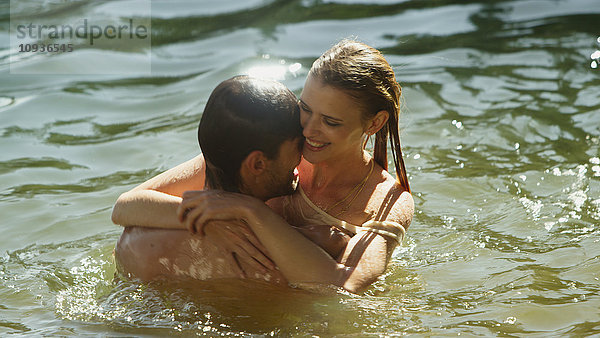 Zärtliches Paar  das sich umarmt und im sonnigen See schwimmt