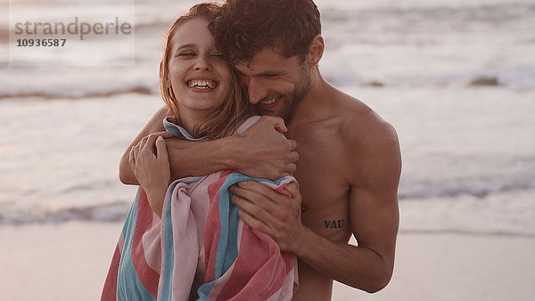 Zärtliches junges Paar  das sich am Strand umarmt