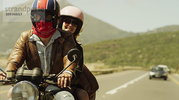 Junges Paar fährt Motorrad auf sonniger Straße