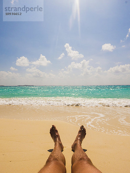 Mann beim Sonnenbaden am sonnigen tropischen Strand