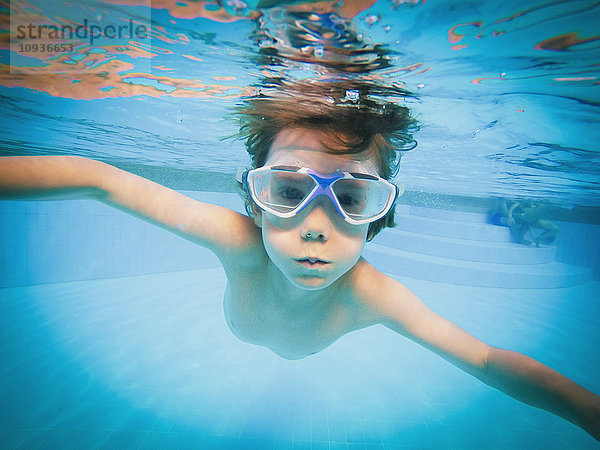 Porträt eines Jungen  der im Schwimmbad unter Wasser schwimmt