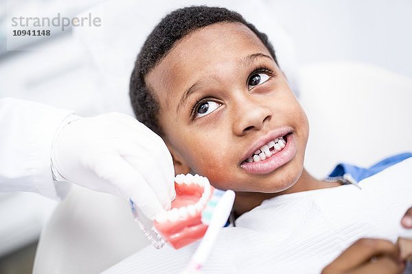 Zahnarzt zeigt einem Jungen seinen Zahnersatz