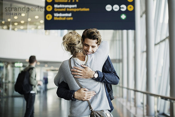 Glücklicher Geschäftsmann umarmt Kollegen am Flughafen