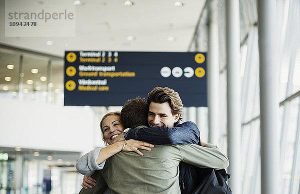 Liebevolle Geschäftsfreunde  die sich am Flughafen umarmen