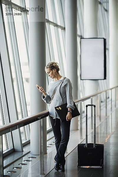 Geschäftsfrau mit Smartphone am Flughafen