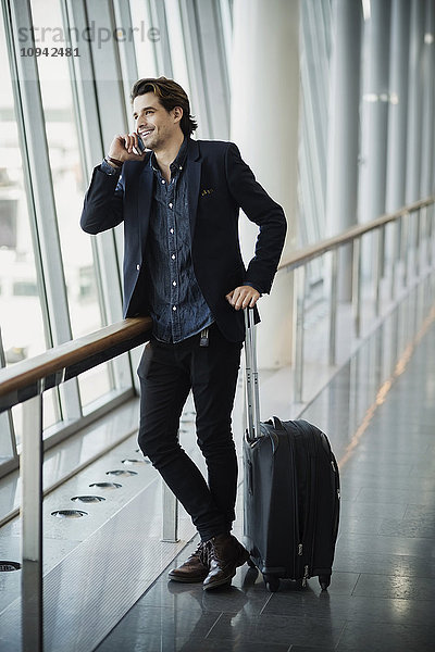 Glücklicher Geschäftsmann mit Smartphone am Flughafen
