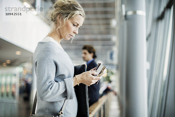 Seitenansicht der Geschäftsfrau mit Smartphone am Flughafen