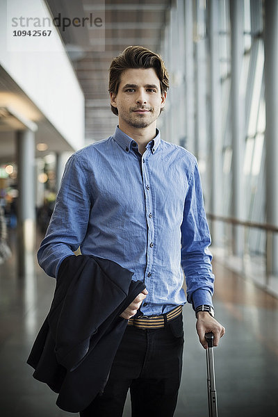 Porträt eines selbstbewussten Geschäftsmannes mit Gepäck am Flughafen