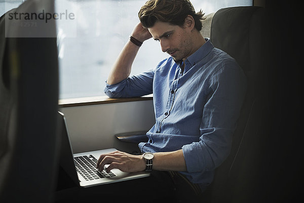 Geschäftsmann mit Laptop auf Reisen im Zug