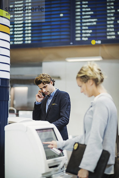 Geschäftsleute mit Check-in-Maschinen am Flughafen