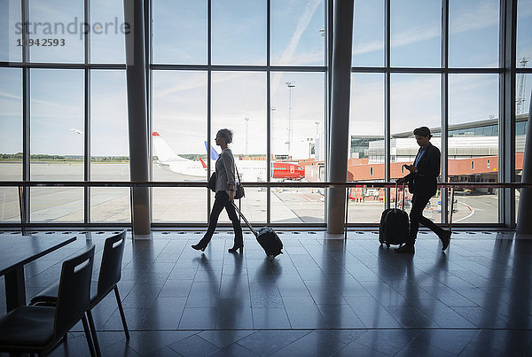 Seitenansicht von Geschäftsleuten mit Gepäck am Flughafen