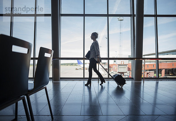 Seitenansicht der Geschäftsfrau mit Gepäck am Flughafen