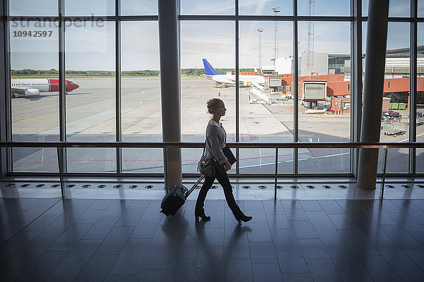 Geschäftsfrau zu Fuß mit Gepäck am Flughafen