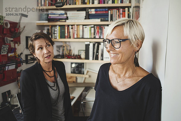 Lächelnde Industriedesigner im Gespräch mit Kollegen im Home Office