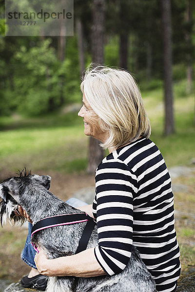 Seitenansicht einer fröhlichen Seniorin mit Hund auf dem Feld