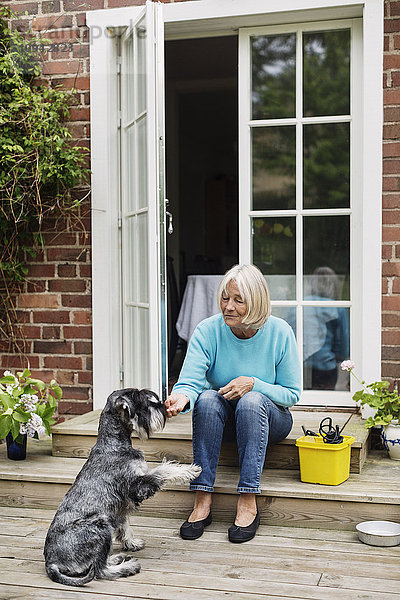 Seniorin sitzend mit Hund vor der Tür